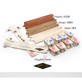 A set of chopstick making materials including wooden blanks in Maple, Paduak, and Wenge, along with canvas sleeves in blue and red, displayed on a table.